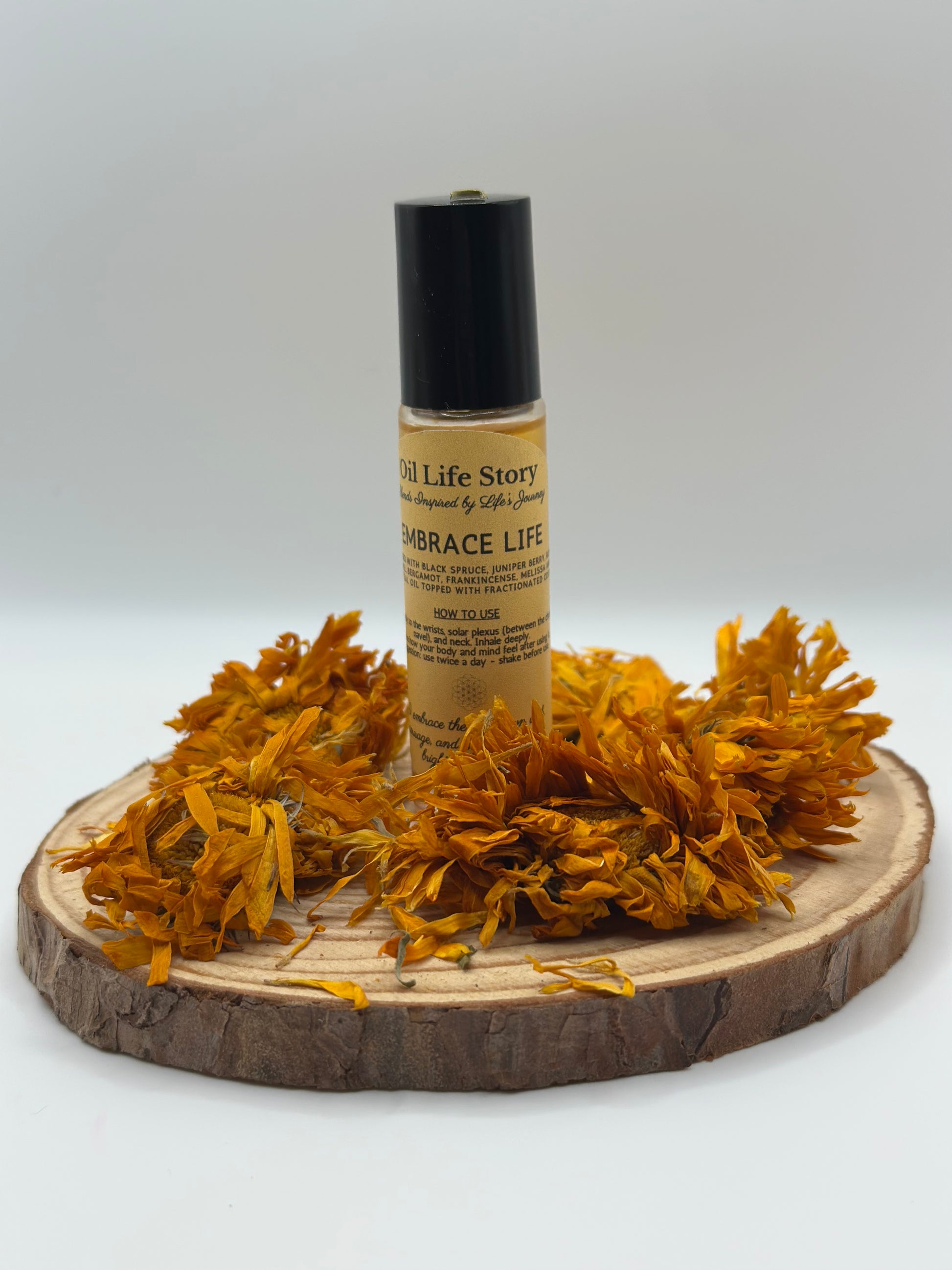 Embrace Life essential oil blend surrounded by orange dried flowers on a wooden plate
