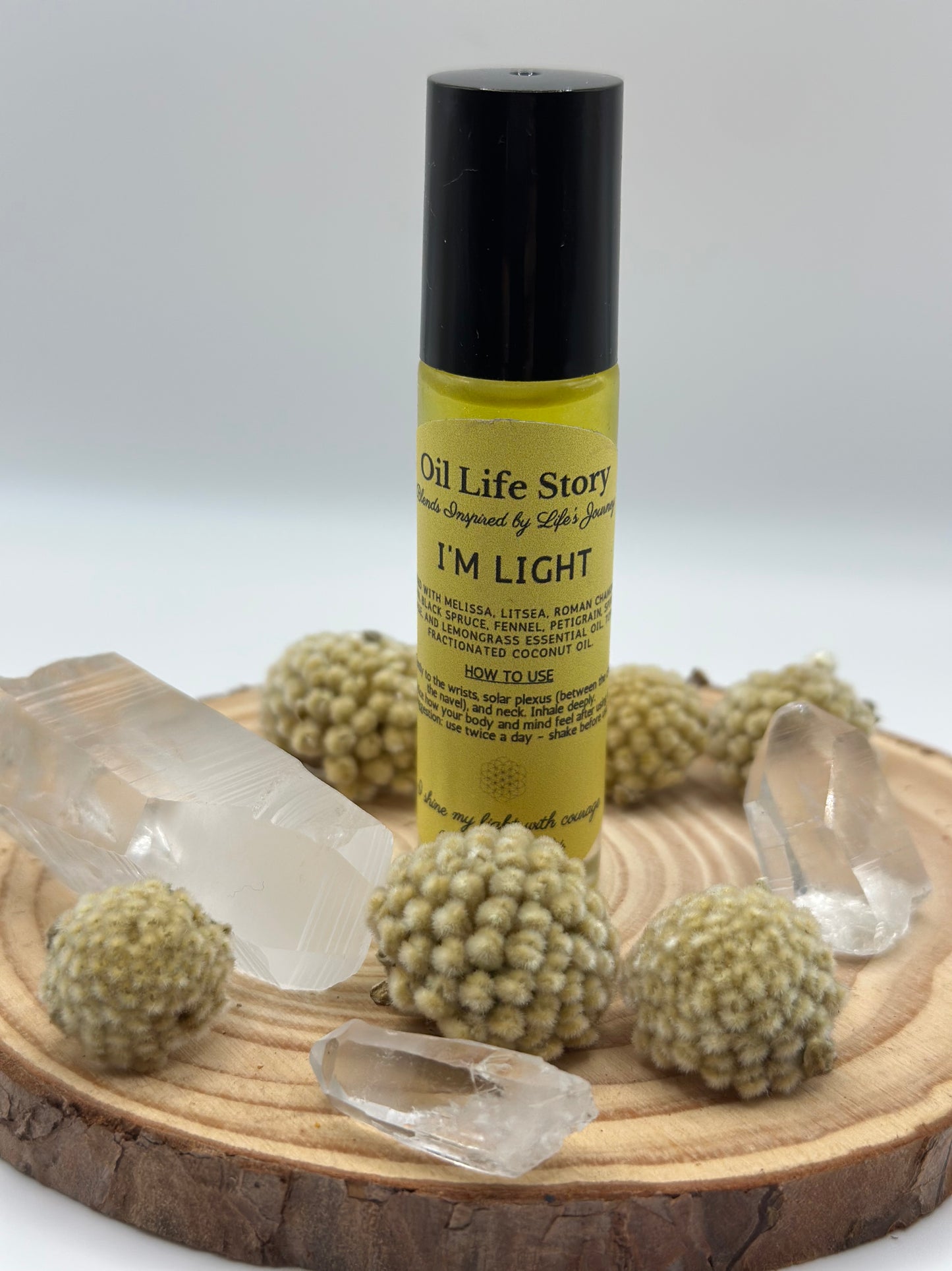I Am Light essential oil blend with clear quartz and textured botanicals on a wooden plate