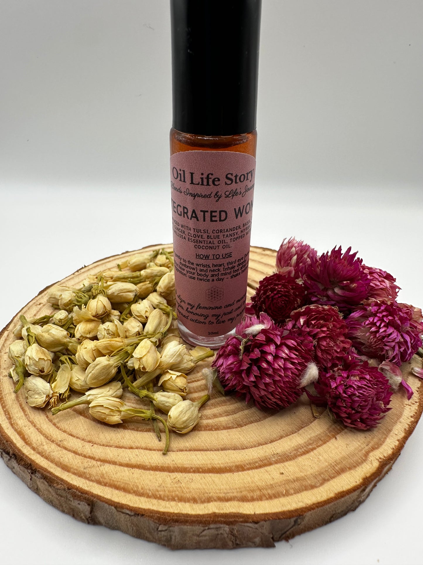 Integrated Woman essential oil blend with dried botanicals and raspberries on a wooden plate